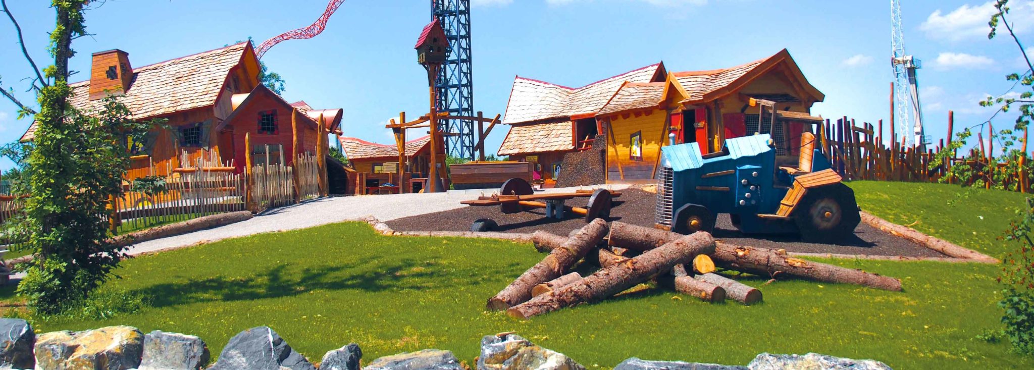 Bauernhof Spielplatz mit einem blauen Traktor und Holzstämmen auf dem Boden.